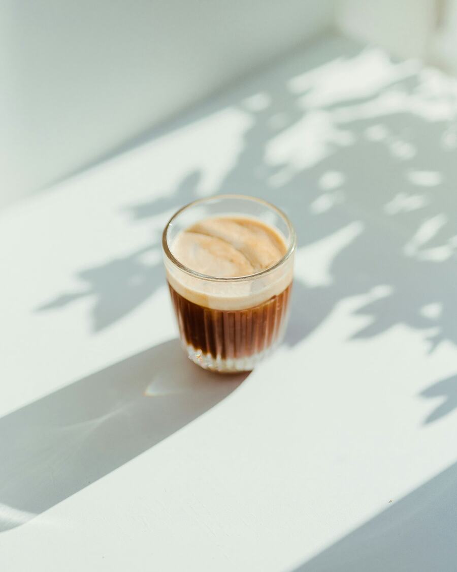 A cup of coffee on linen with soft window shadows