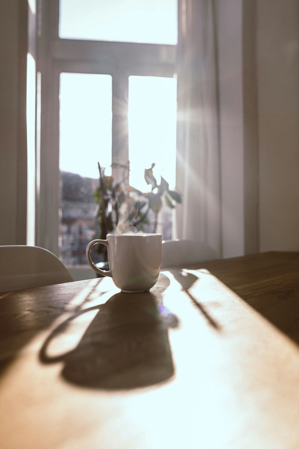 Soft morning light falling through a window onto a table with a coffee cup