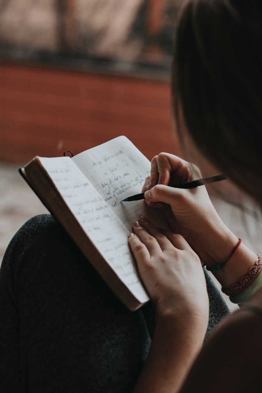 A hand writing in a journal in soft daylight